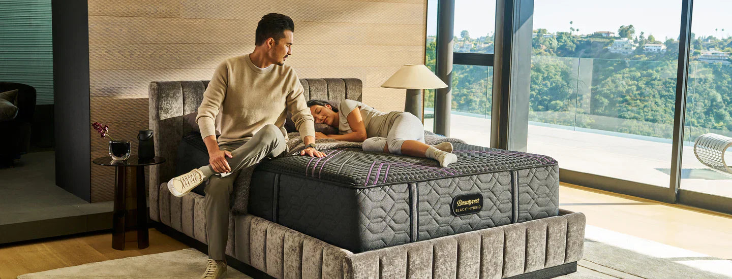 Man sitting and woman laying on a Queen Beautyrest Mattresses