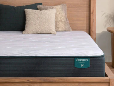 A Beautyrest Harmony mattress with a white quilted top on a wooden bed frame, designed for consistent support, pressure relief, and a lifted, traditional mattress feel.