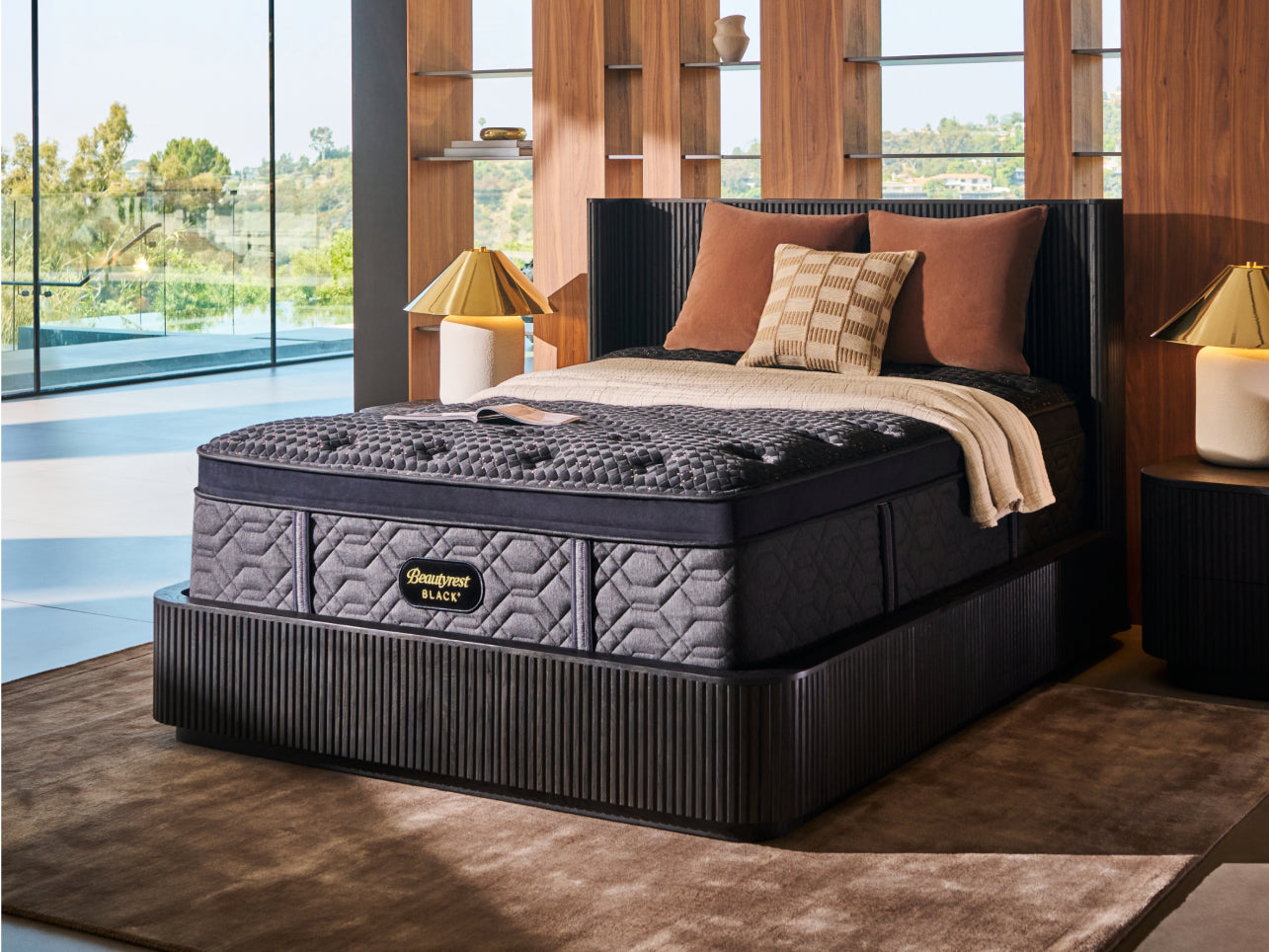 Beautyrest Black mattress sitting in a dark green bedframe with 3 pillows and a blanket on top of the mattress