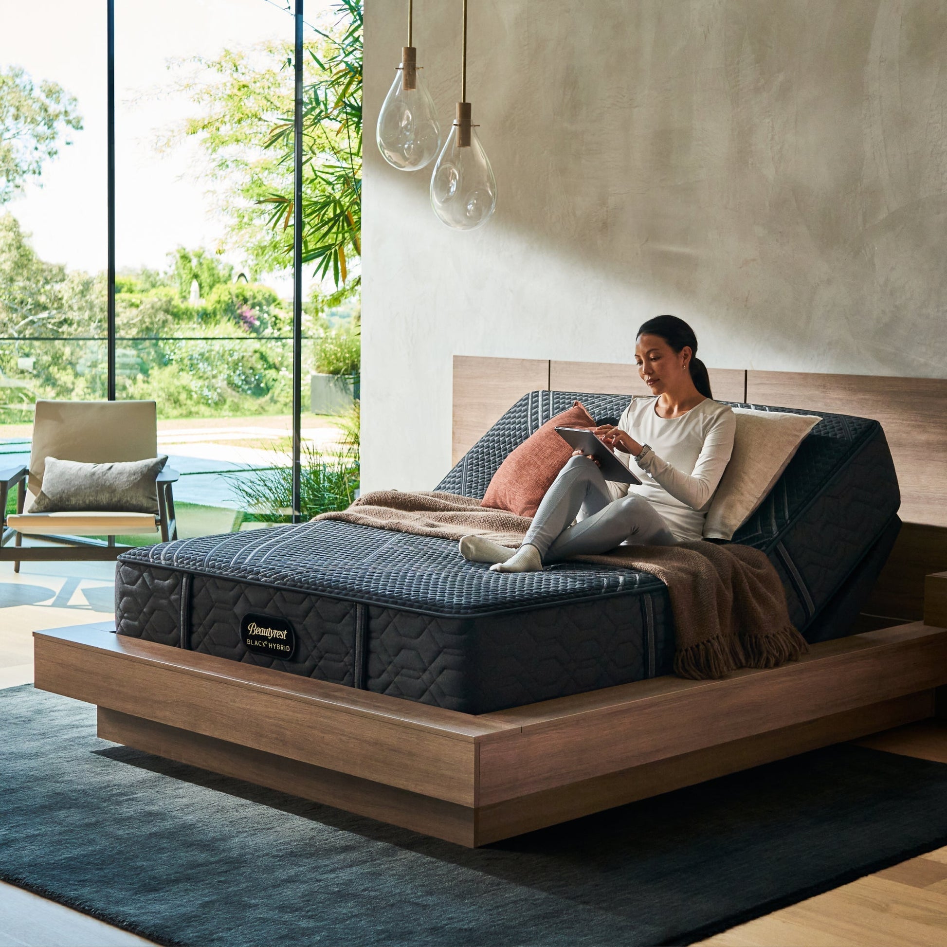 Woman sitting on BeautyRest Plush Hybrid mattress sitting on an adjustable base || series: Series One || feel: Plush
