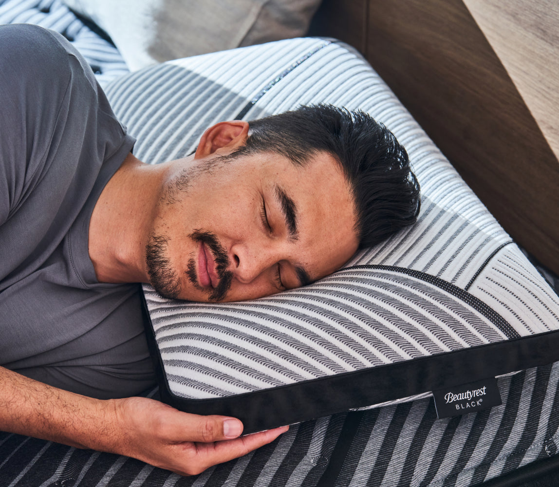 Man laying on his left side with his head on a Beautyrest Black pillow