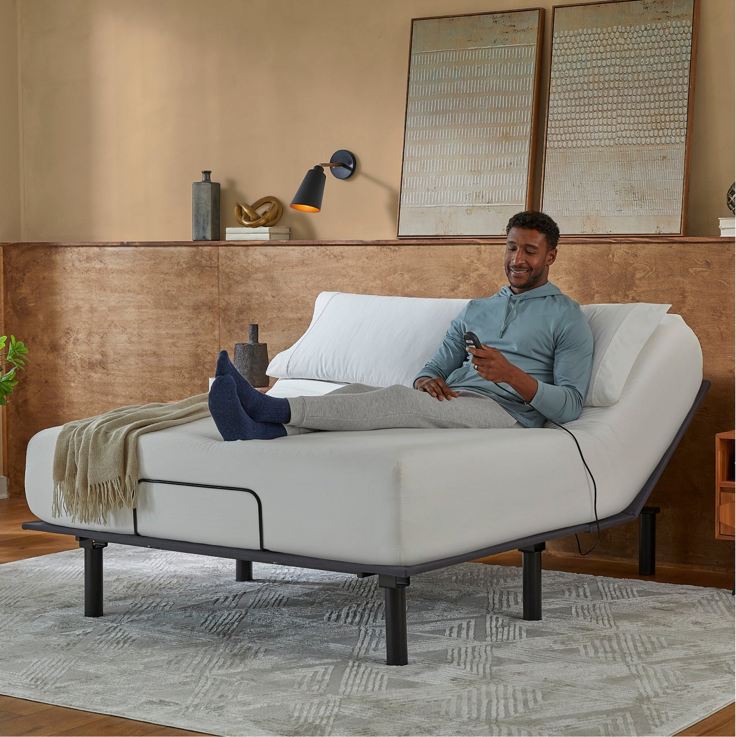 Man sitting in a Baselogic Bronze Adjustable Base with a white mattress on top of it.