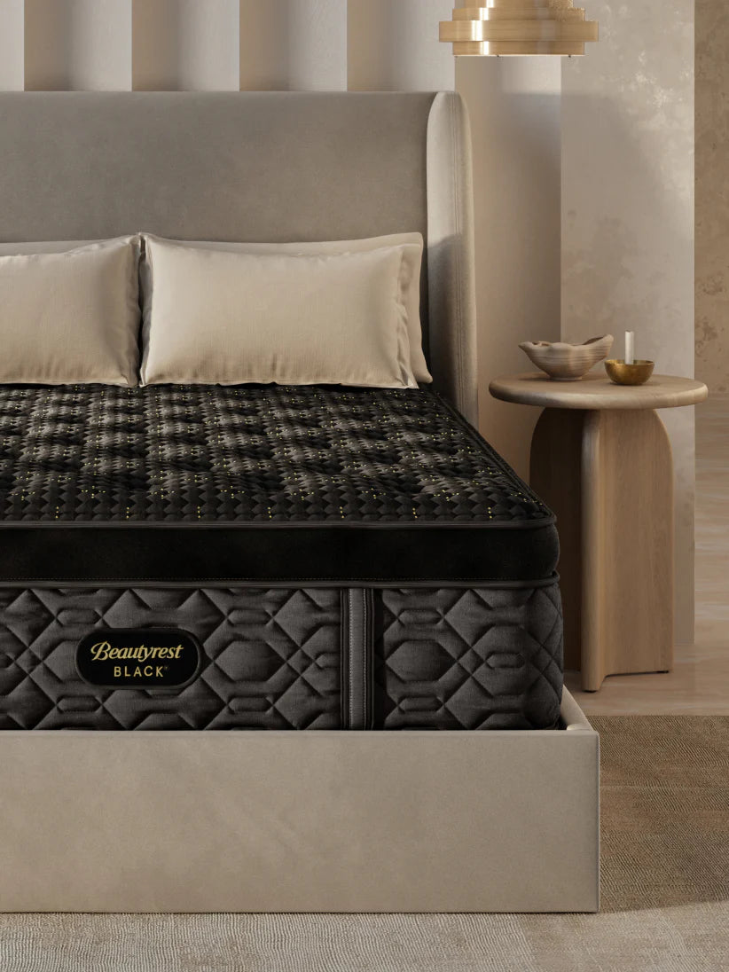 A luxurious black Beautyrest mattress on a sleek upholstered bed frame in a modern bedroom setting.