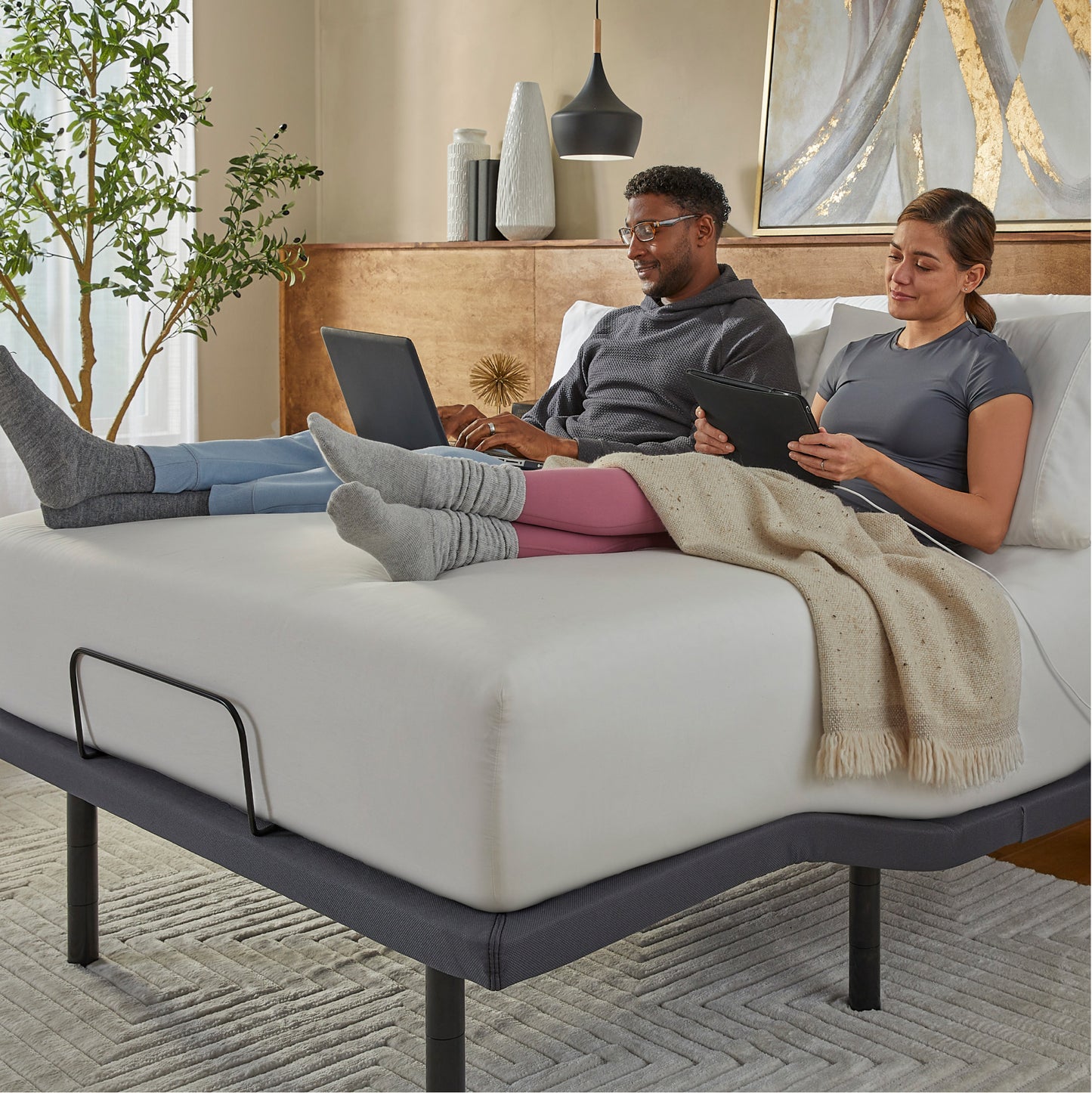 Man and Woman sitting in a Baselogic Gold Adjustable Base with a white mattress on top of it. || level: Gold