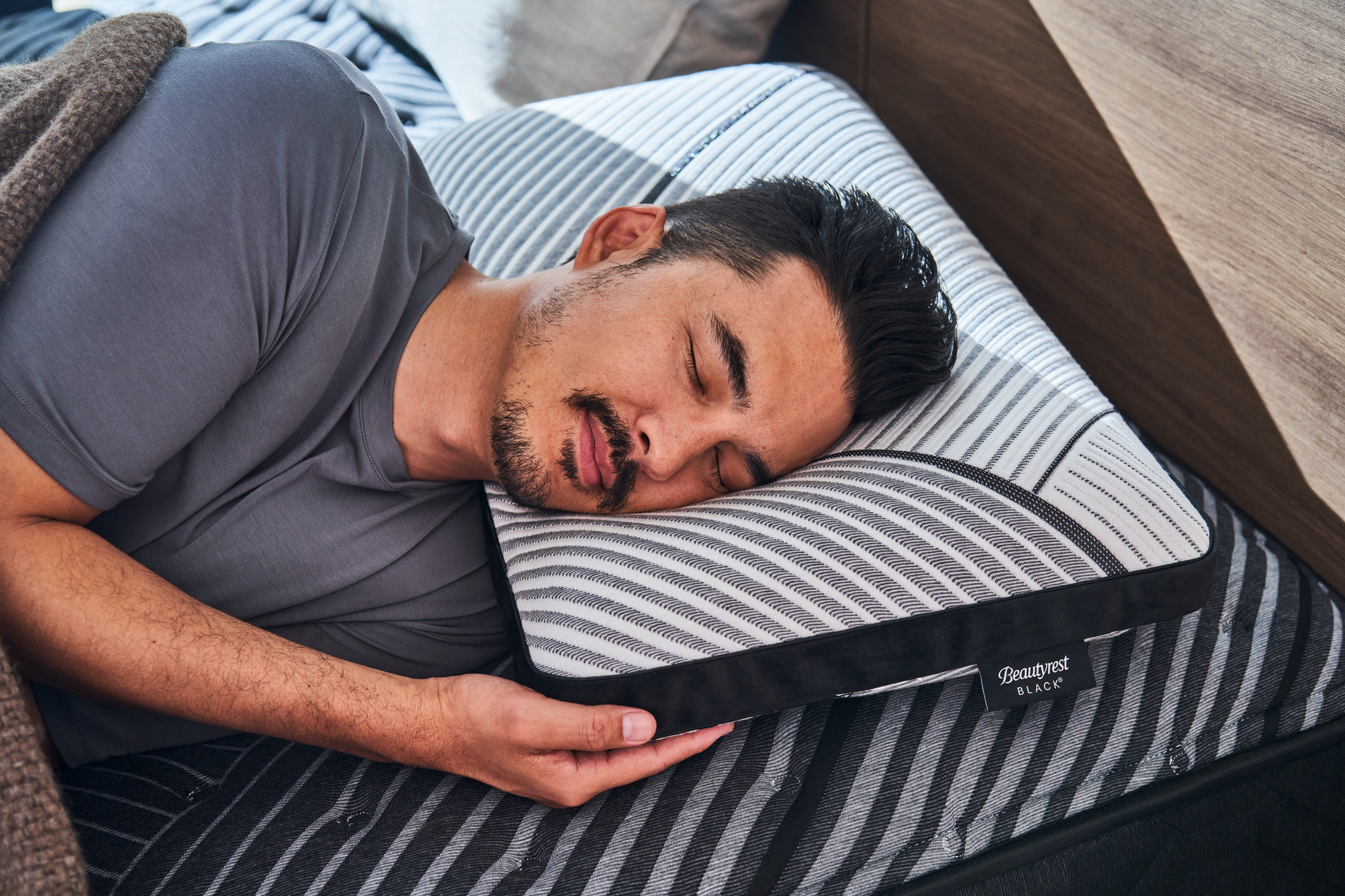 Man laying asleep on his left side with his head on a Beautyrest Black foam pillow