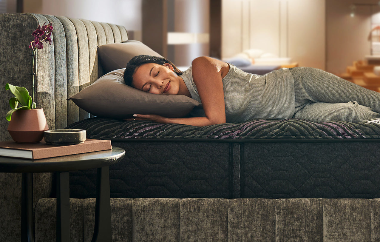 A woman testing a Beautyrest bed in a mattress show room.