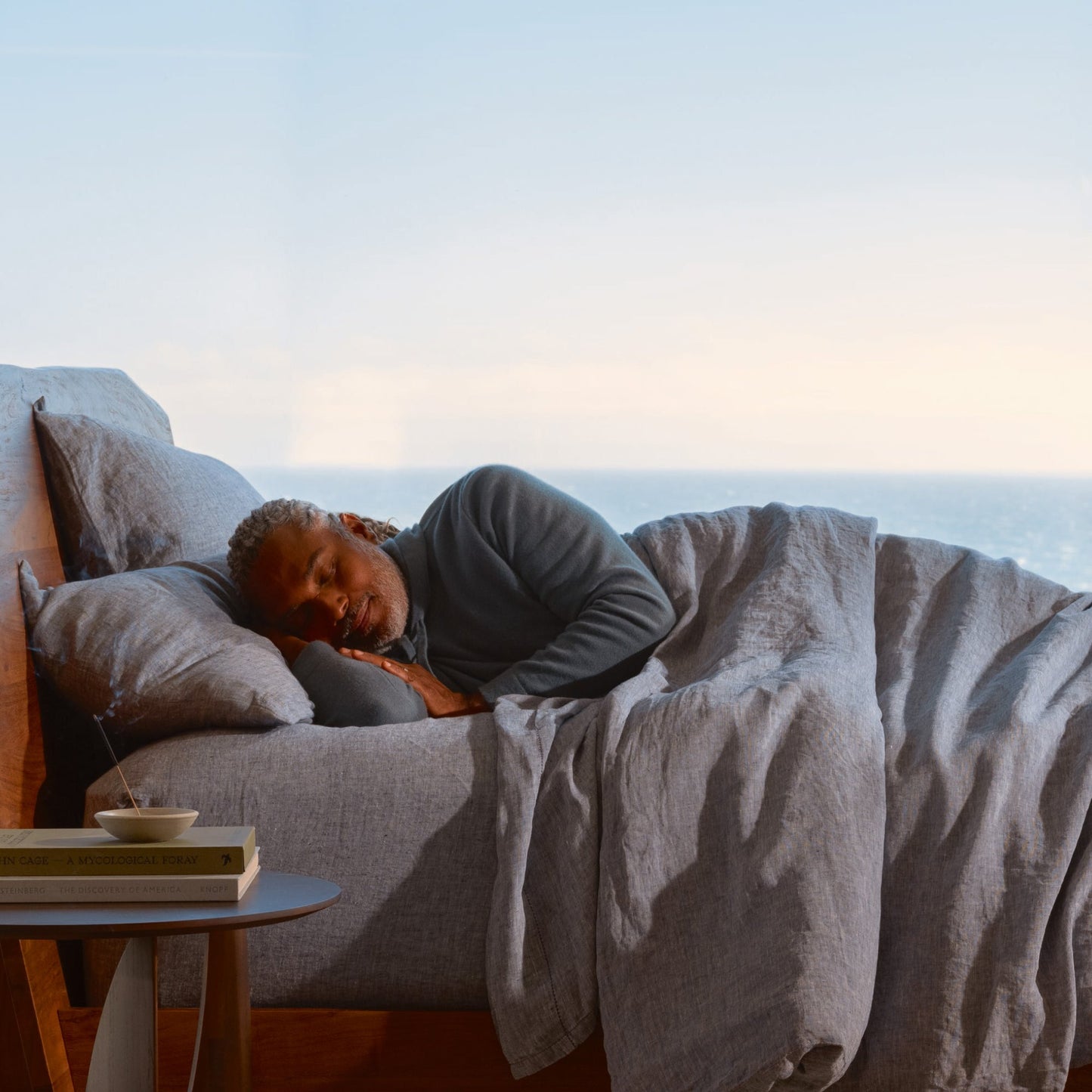 A man sleeping next to incense on a Beautyrest Harmony Lux mattress || series: Premier Anchor Island || feel: plush