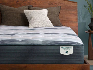 A Beautyrest Harmony Lux mattress with a quilted white and grey top on a wooden bed frame, featuring advanced cooling, enhanced support, and additional memory foam for a luxurious feel.