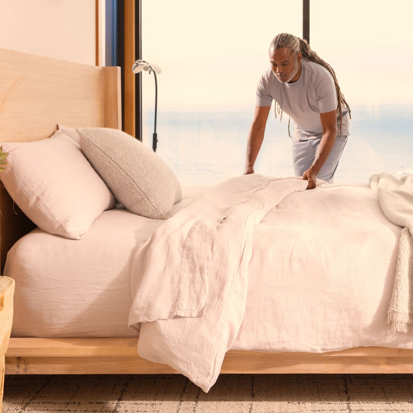 A man making the bed of a Beautyrest Harmony hybrid Exceptional Driftwood Bay mattress || series: Exceptional Driftwood Bay